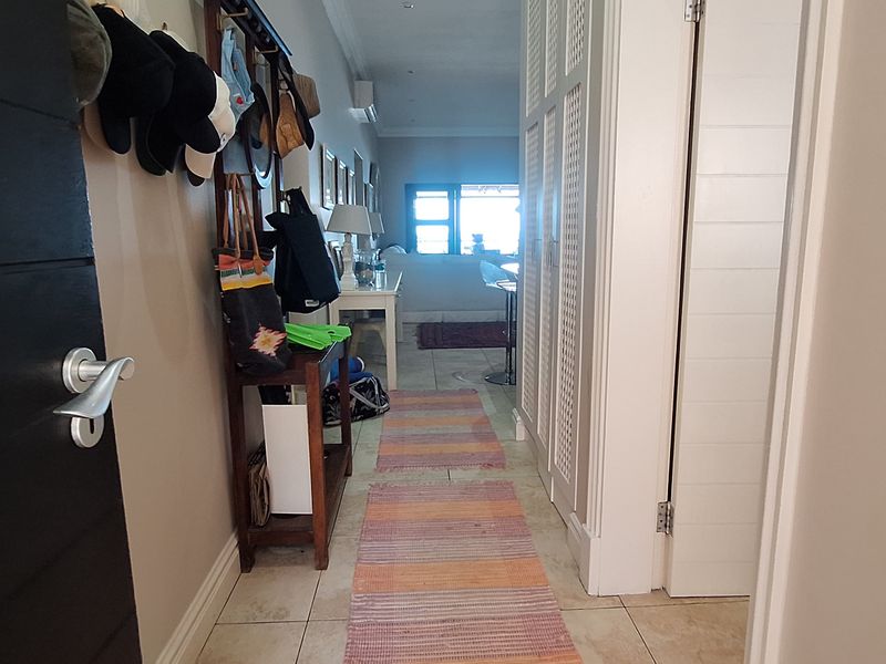 A functional hallway featuring tiled flooring and built-in storage cupboards, providing a direct transition into the main living area of the apartment.