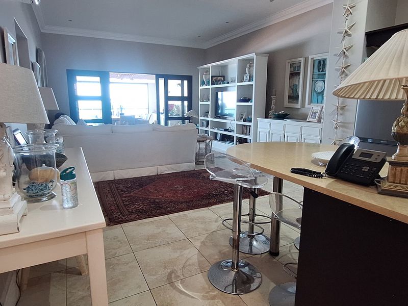 Spacious open-plan living and kitchen area featuring tiled flooring, built-in cabinetry, and large sliding doors leading to an outdoor space.