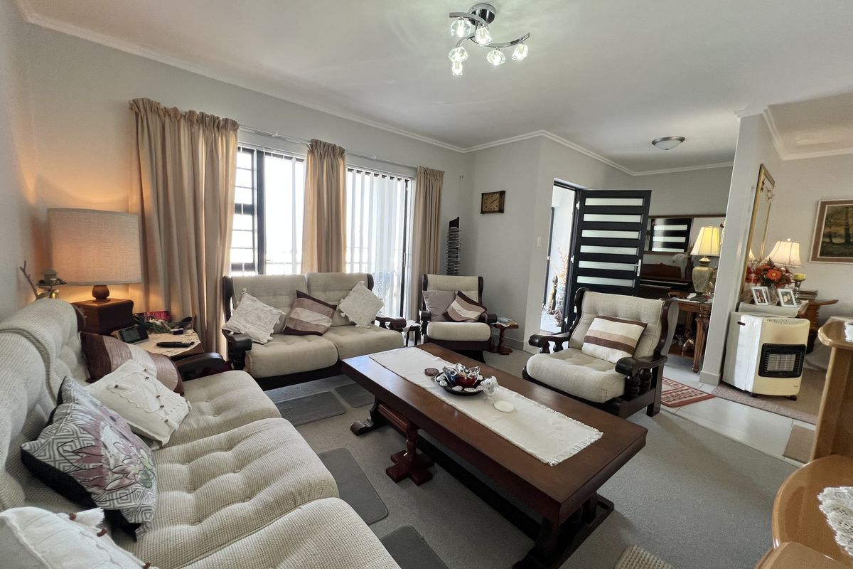A comfortable living room featuring neutral carpeting, coved ceilings, and sliding glass doors that provide natural light.