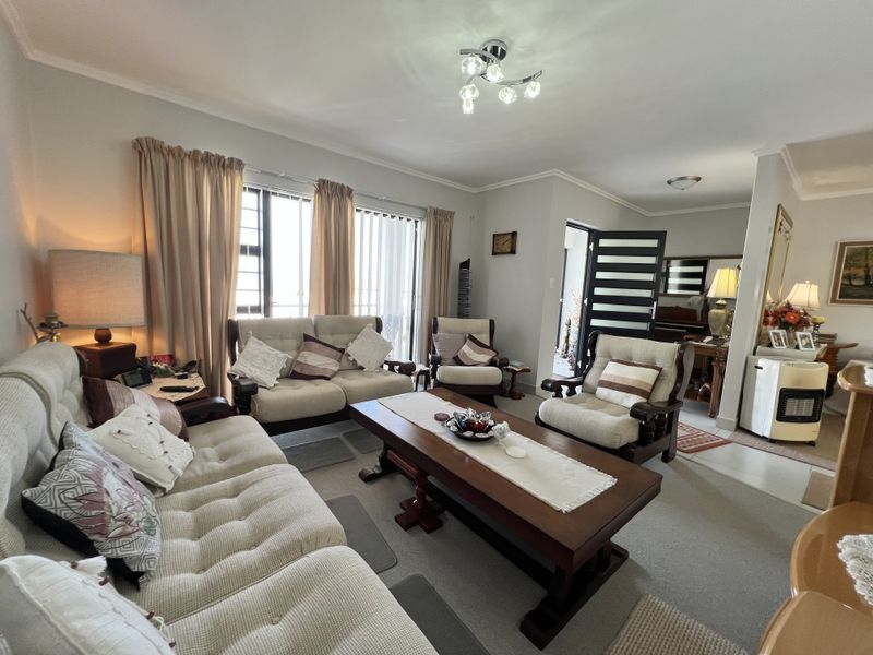 A comfortable living room featuring neutral carpeting, coved ceilings, and sliding glass doors that provide natural light.