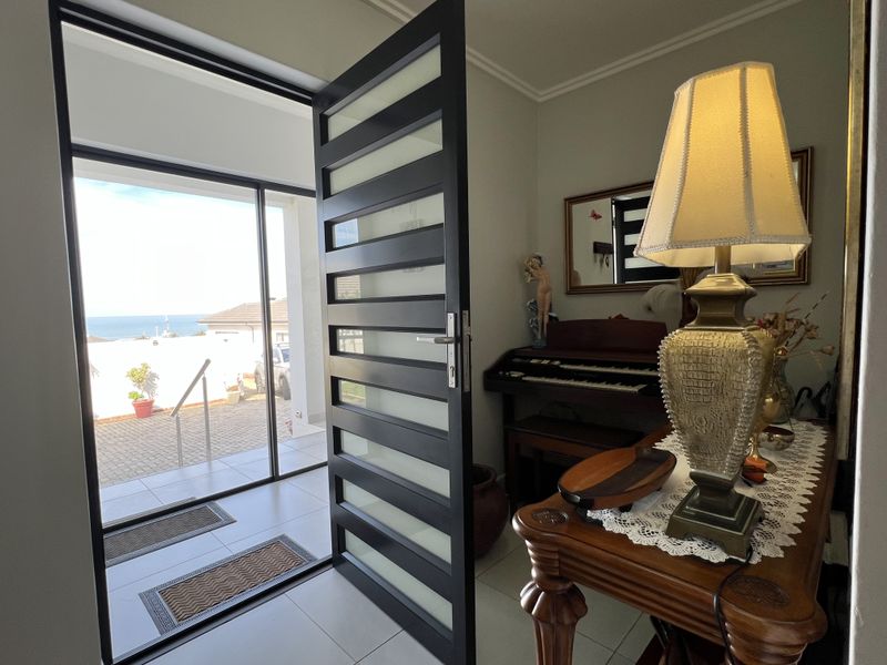 Welcoming entrance area featuring a contemporary glass-panelled door, tiled flooring, and a large sidelight providing natural light and views of the exterior.