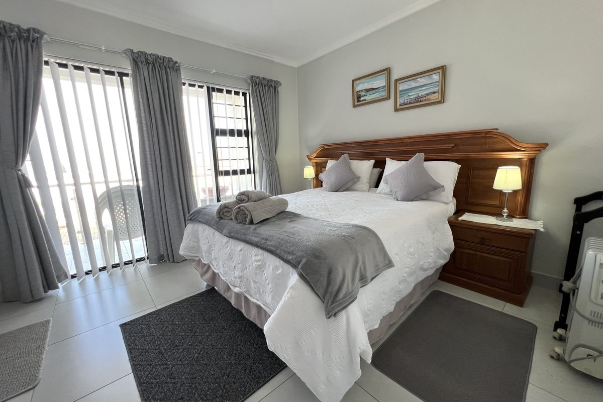 A well-maintained bedroom featuring tiled flooring, a built-in wooden headboard, and a sliding glass door providing access to an outdoor patio area.