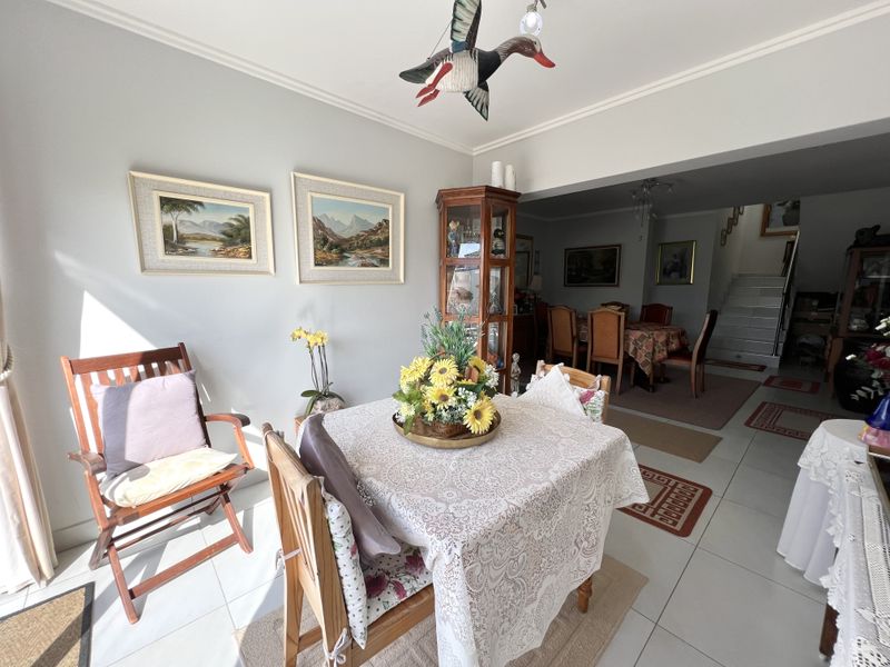 Open plan living and dining area featuring tiled flooring and a staircase, providing a versatile space for family living and entertaining.