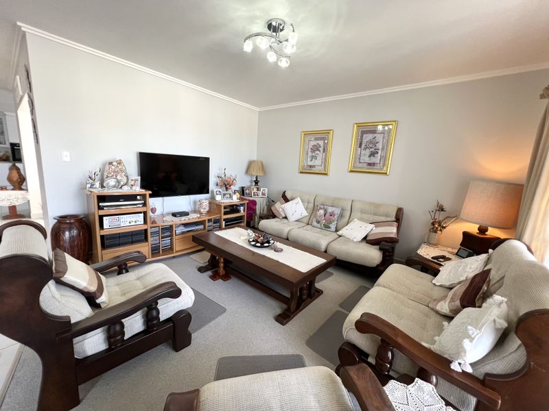 A comfortable living room featuring neutral wall tones, coving, and a central ceiling light fixture, providing a functional and well-maintained space.