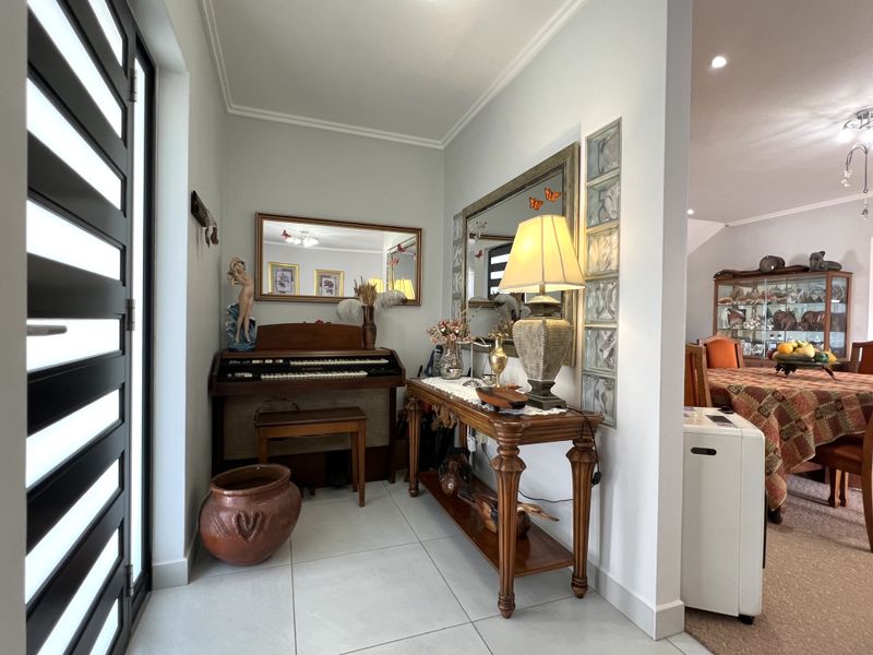 A bright entrance hall featuring modern tiled flooring, a decorative glass block partition, and direct access to the main living area.