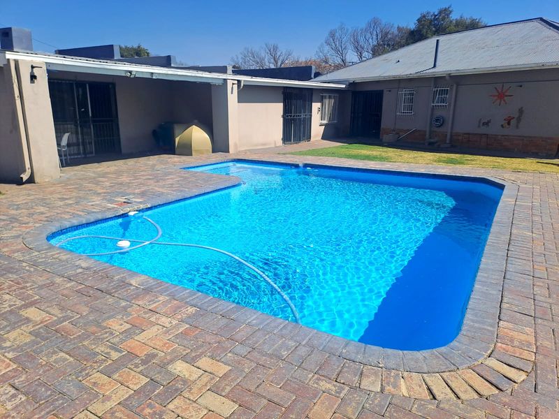 A well-maintained swimming pool area featuring brick paving, a covered patio, and secure access points to the main house.