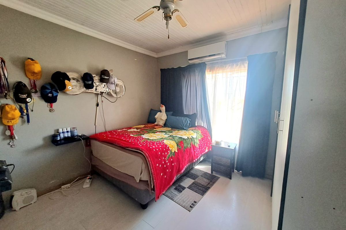 A functional bedroom featuring a ceiling fan, split-system air conditioning unit, and built-in wardrobe storage.