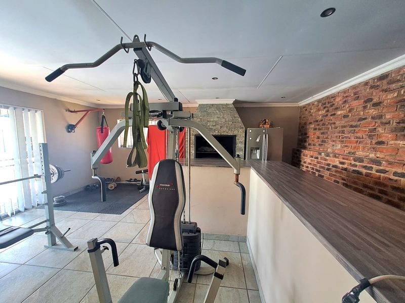 A multi-purpose gym area featuring a built-in braai, exposed brick wall, breakfast bar, and tiled flooring.