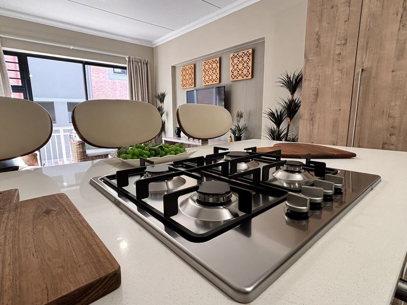 Modern open-plan living area featuring a sleek kitchen island with a built-in gas hob and quartz countertops, seamlessly connecting to the living space.