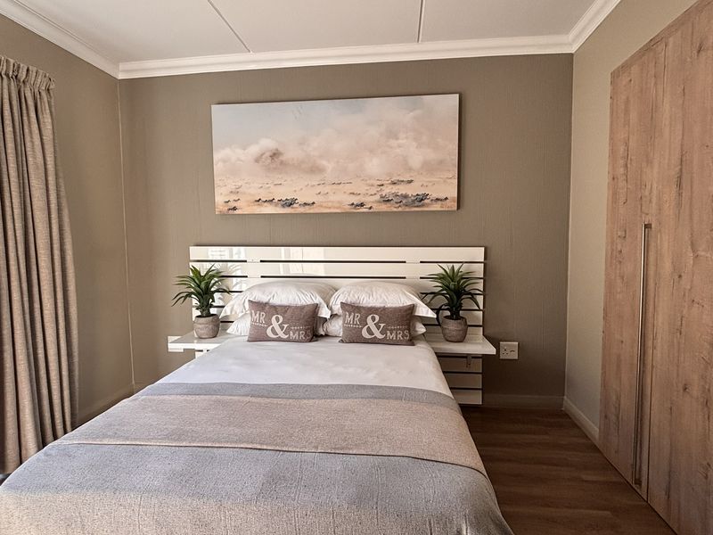 A well-maintained bedroom featuring laminate flooring, a built-in wardrobe, and a sliding glass door providing access to a balcony.
