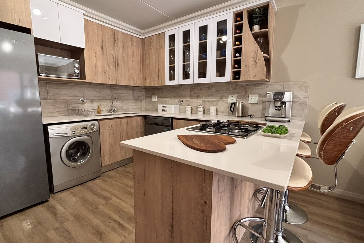 Modern kitchen featuring wood-finish cabinetry, stone countertops, a gas hob, and integrated appliances, offering a functional and stylish cooking space.