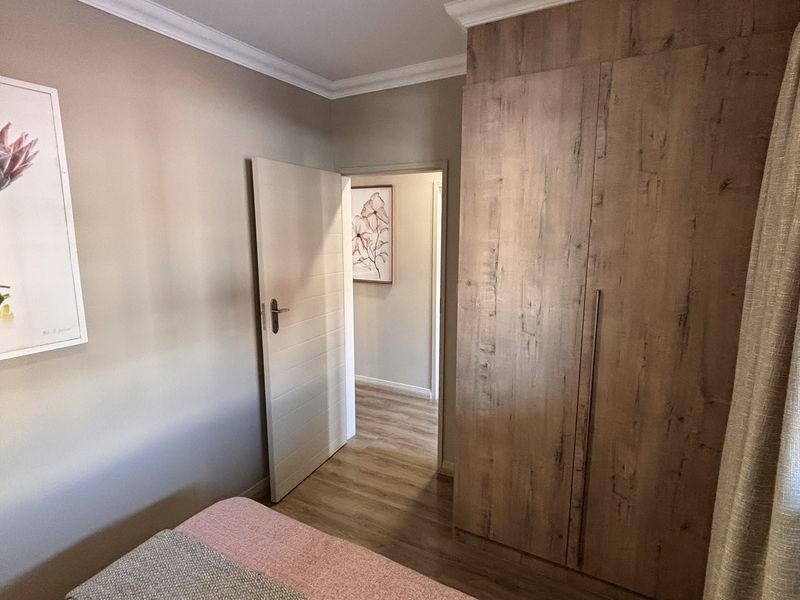 A well-maintained bedroom featuring wood-look laminate flooring, built-in cabinetry, and neutral wall finishes, providing a clean and functional living space.