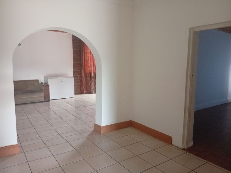 An open-plan living area featuring tiled flooring and a distinctive arched doorway connecting to an adjacent space.