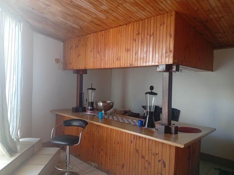 A dedicated bar area featuring a built-in timber counter, matching timber panelled ceiling, and tiled flooring, offering a classic entertainment space.