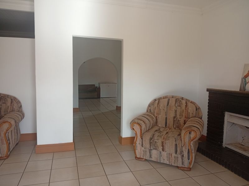 Living room featuring a brick fireplace, ceramic floor tiles, and an arched doorway leading to an adjacent space.