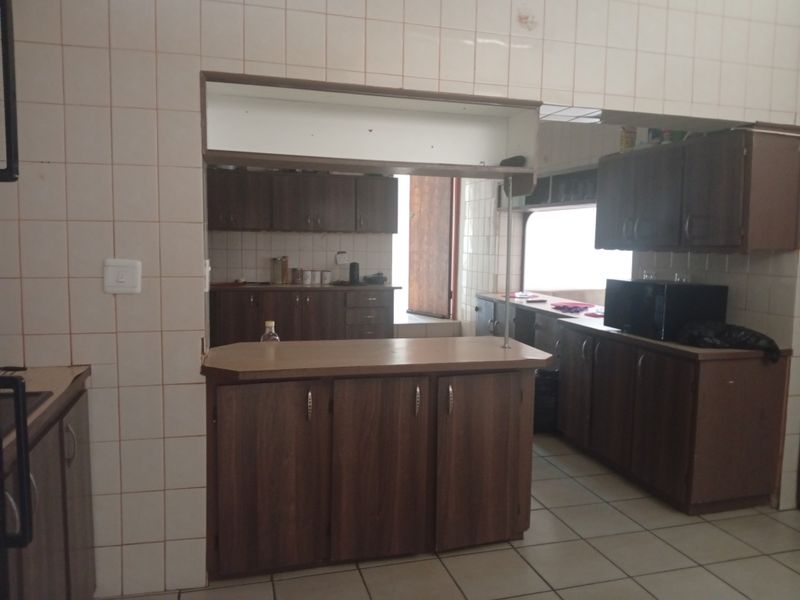 A dated kitchen featuring dark wood-look cabinetry, tiled walls, and a breakfast bar counter, offering potential for a modern renovation.