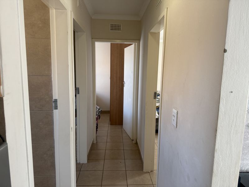 A functional hallway featuring tiled flooring and multiple internal door access points, connecting various rooms within the property.