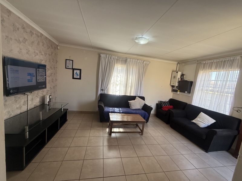 A functional living room featuring tiled flooring and a wall-mounted inverter system, providing a practical and comfortable space for daily relaxation.