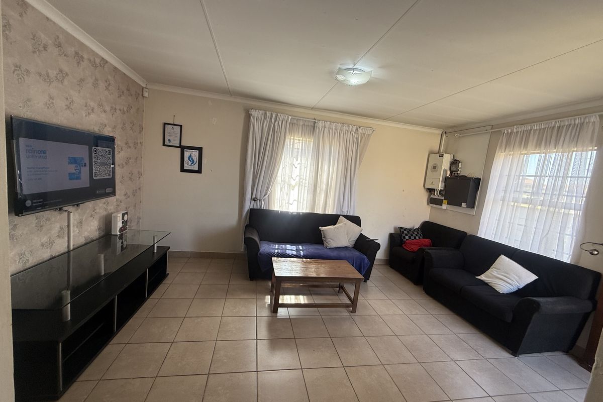 A functional living room featuring tiled flooring and a wall-mounted inverter system, providing a practical and comfortable space for daily relaxation.