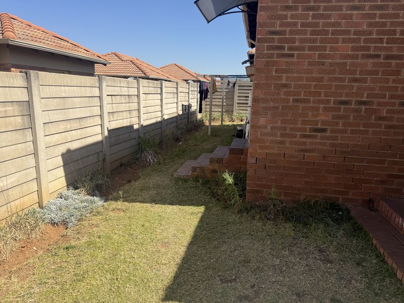 A side garden area featuring a brick facade, concrete boundary wall, and brick steps leading to the property.