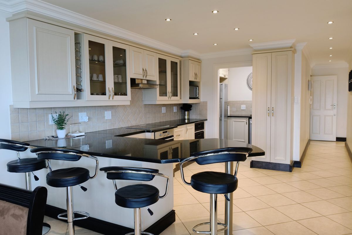 Modern kitchen featuring granite countertops, built-in appliances, ample cabinetry, and tiled flooring, with an open-plan layout and recessed lighting.