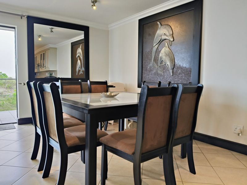 A well-maintained dining area featuring tiled flooring, crown molding, and direct access to an outdoor patio through a sliding glass door.