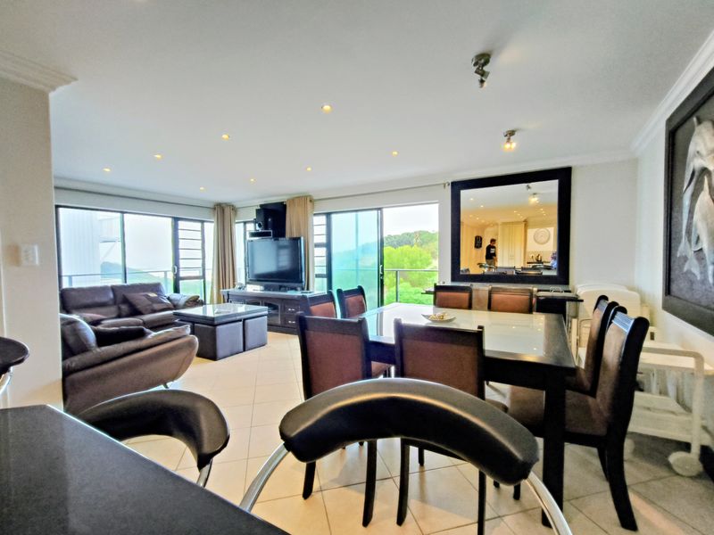 Spacious open-plan living and dining area featuring tiled floors, recessed lighting, and large sliding glass doors leading to an outdoor balcony.