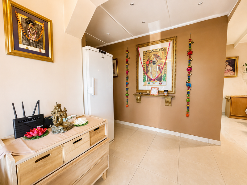 A well-maintained hallway featuring neutral tiled flooring, recessed ceiling lighting, and a decorative archway leading into the adjacent living space.