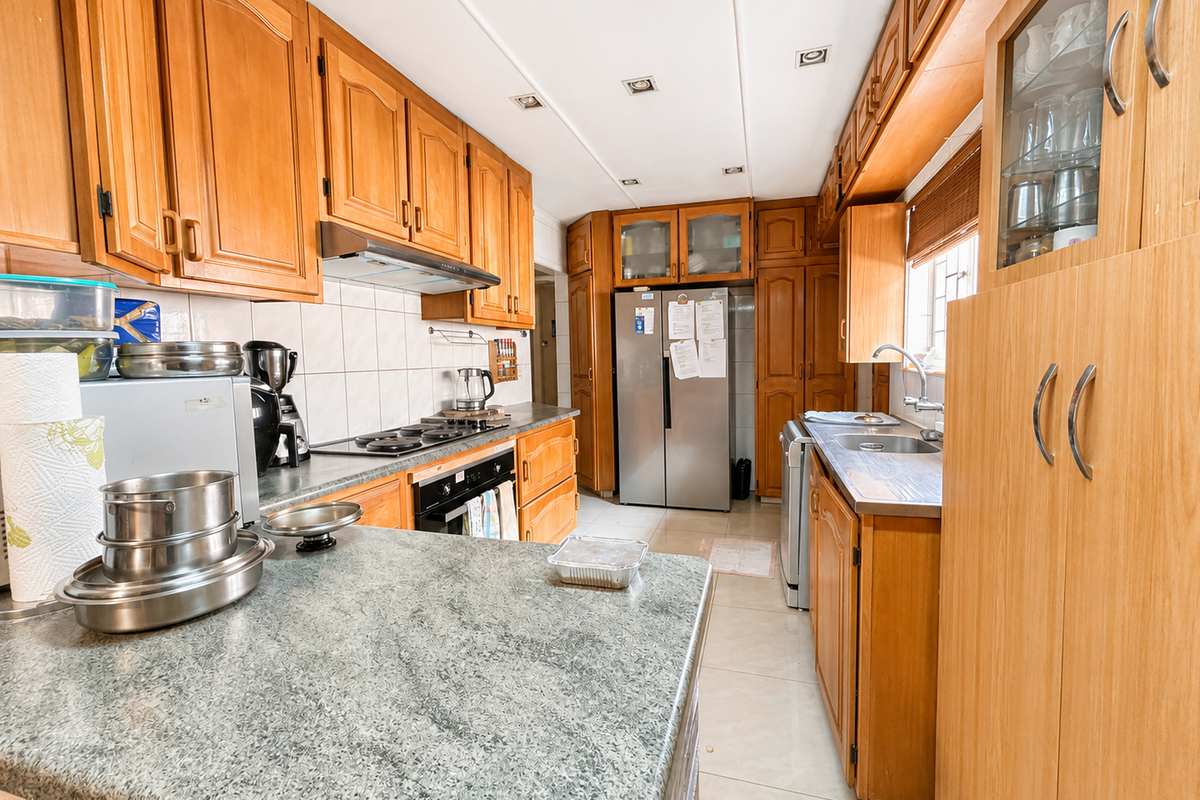 A functional kitchen featuring extensive wooden cabinetry, laminate countertops, a built-in oven with gas hob, and a stainless steel sink.