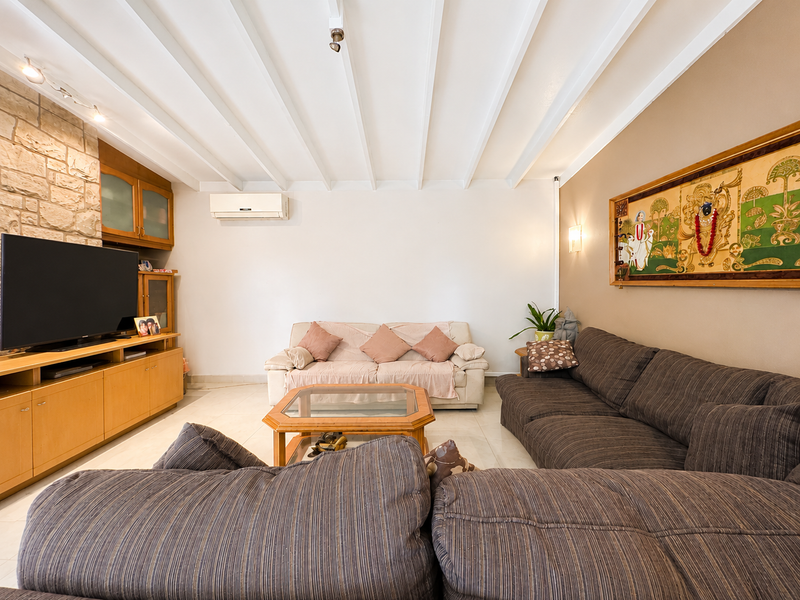 A comfortable living room featuring a stone accent wall, built-in cabinetry, exposed beam ceiling, and a split-system air conditioner.