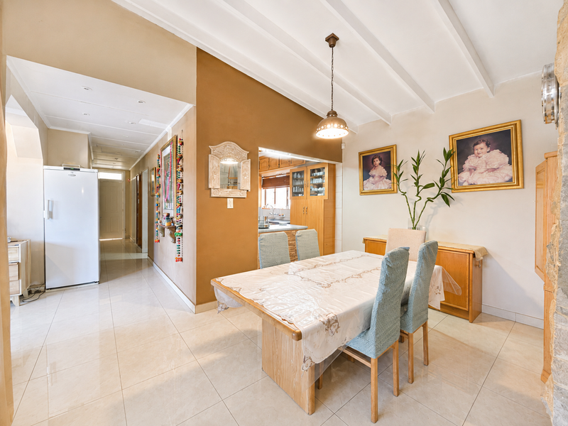 Open plan dining area featuring tiled floors, exposed beam ceiling, and direct access to the adjacent kitchen space.