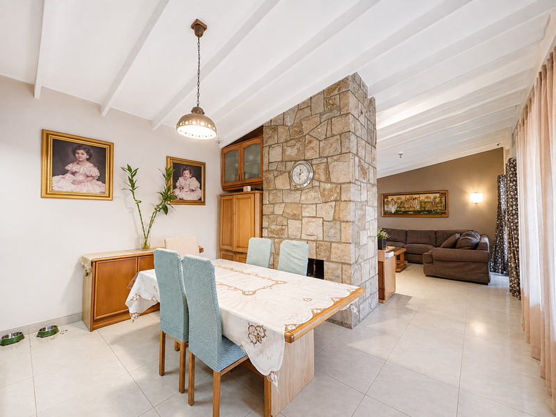 Open plan living and dining area featuring a prominent stone fireplace, exposed beam ceilings, and neutral tiled flooring throughout.