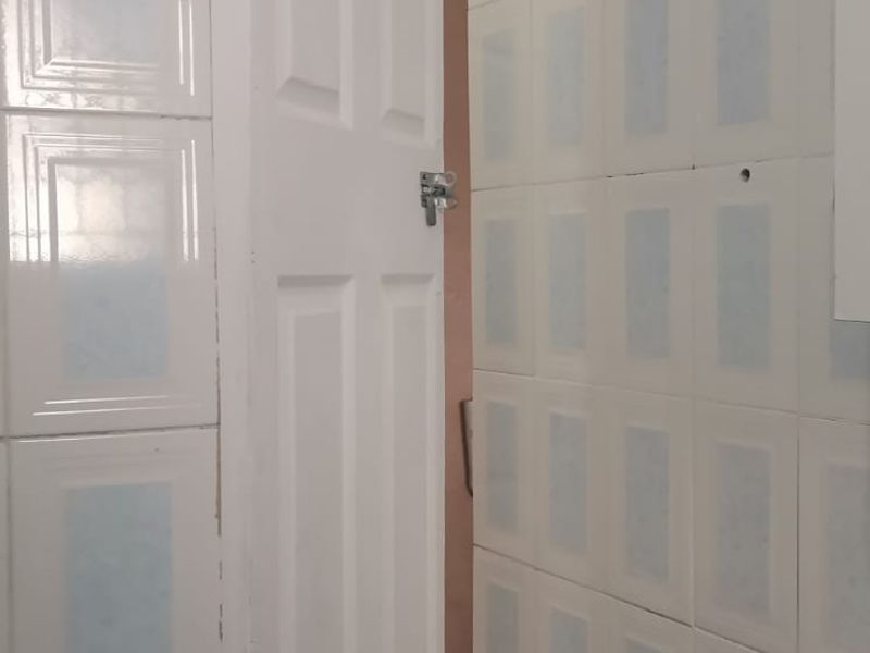 A bathroom featuring tiled walls and flooring with a pedestal basin, currently requiring minor repairs to fixtures and plumbing connections.