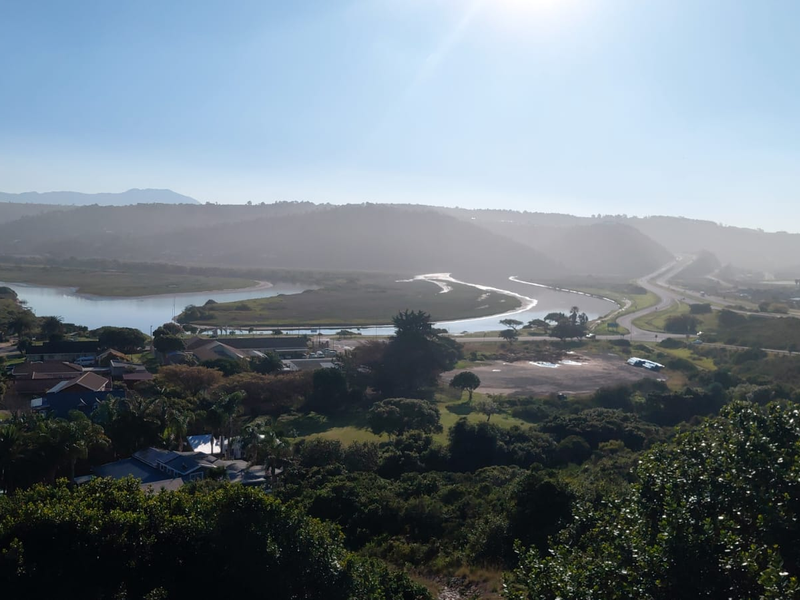 A scenic elevated view overlooking a river estuary, surrounding landscape, and distant hills, capturing the natural beauty of the area.