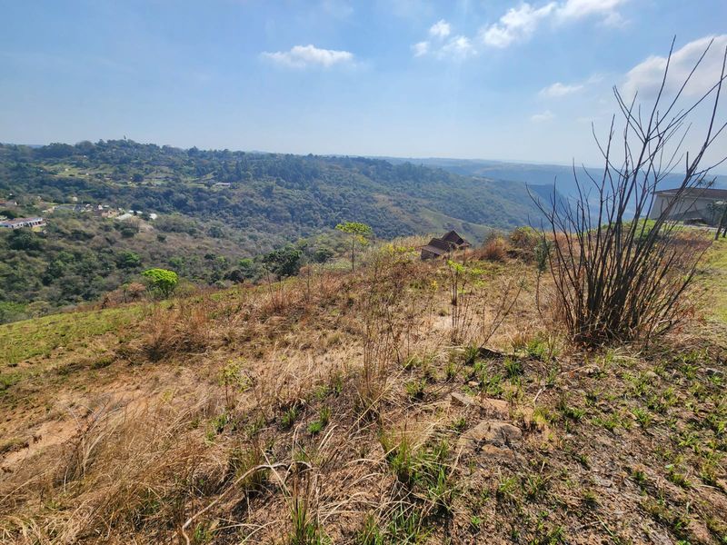Expansive elevated view overlooking a valley and surrounding landscape, showcasing the natural terrain and distant hillside properties.