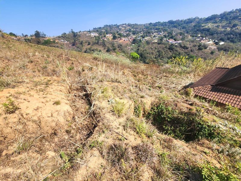Elevated view overlooking a hillside landscape with visible soil erosion and a portion of a tiled roof in the foreground.