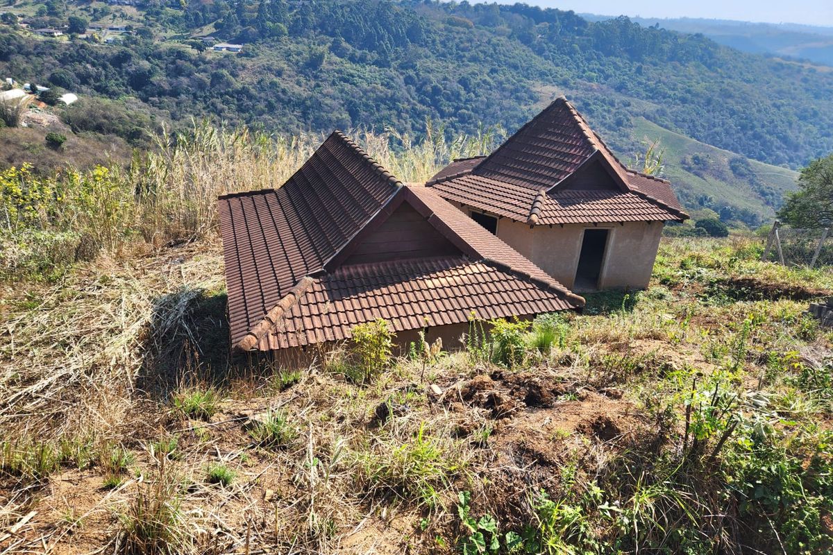 Elevated view of a property featuring two structures with tiled roofs set against a scenic hillside landscape.