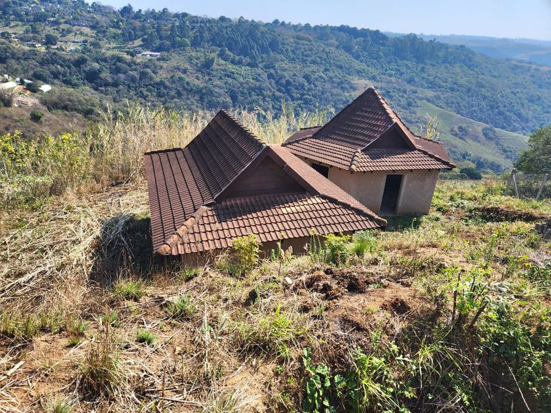 Elevated view of a property featuring two structures with tiled roofs set against a scenic hillside landscape.