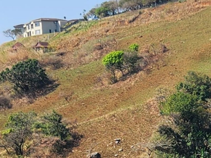 A distant view of a residential property situated on a sloping hillside landscape.