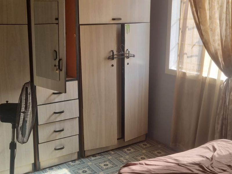 A bedroom featuring tiled flooring and a window with natural light, providing a functional living space.