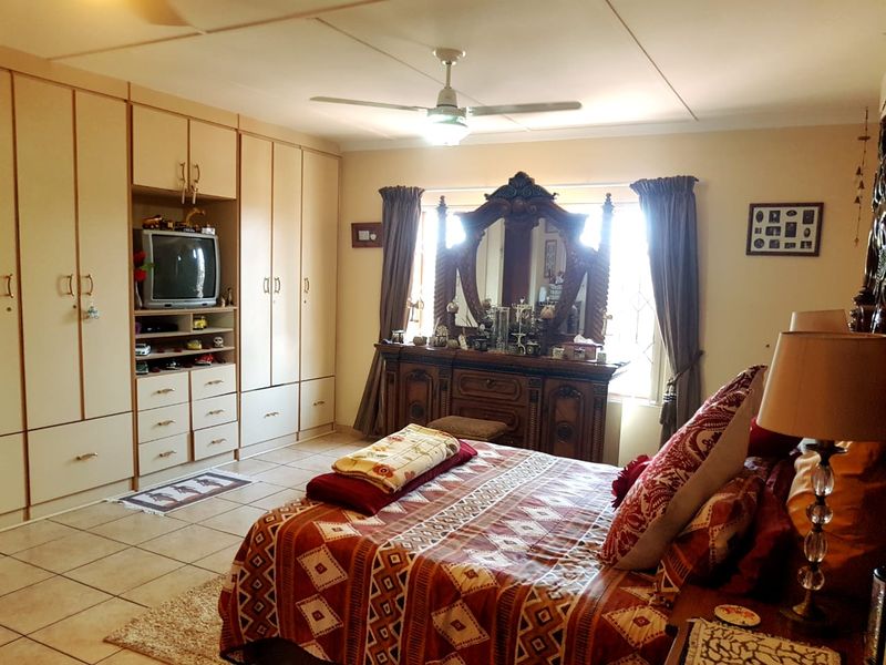 Spacious bedroom featuring extensive built-in cabinetry, tiled flooring, and a ceiling fan, offering ample storage and a functional layout.