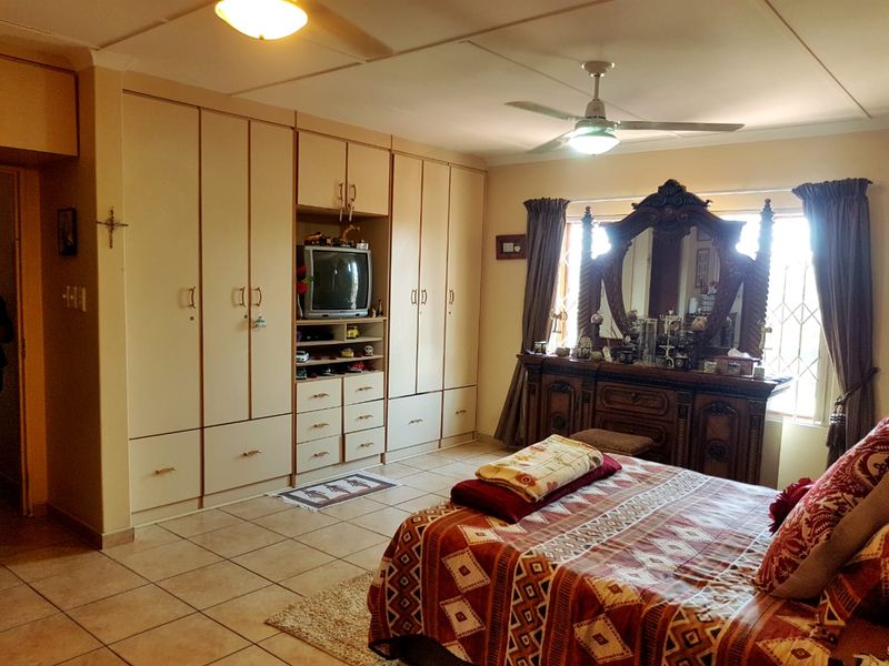Spacious bedroom featuring extensive built-in cabinetry, tiled flooring, and a ceiling fan, offering ample storage and functional living space.