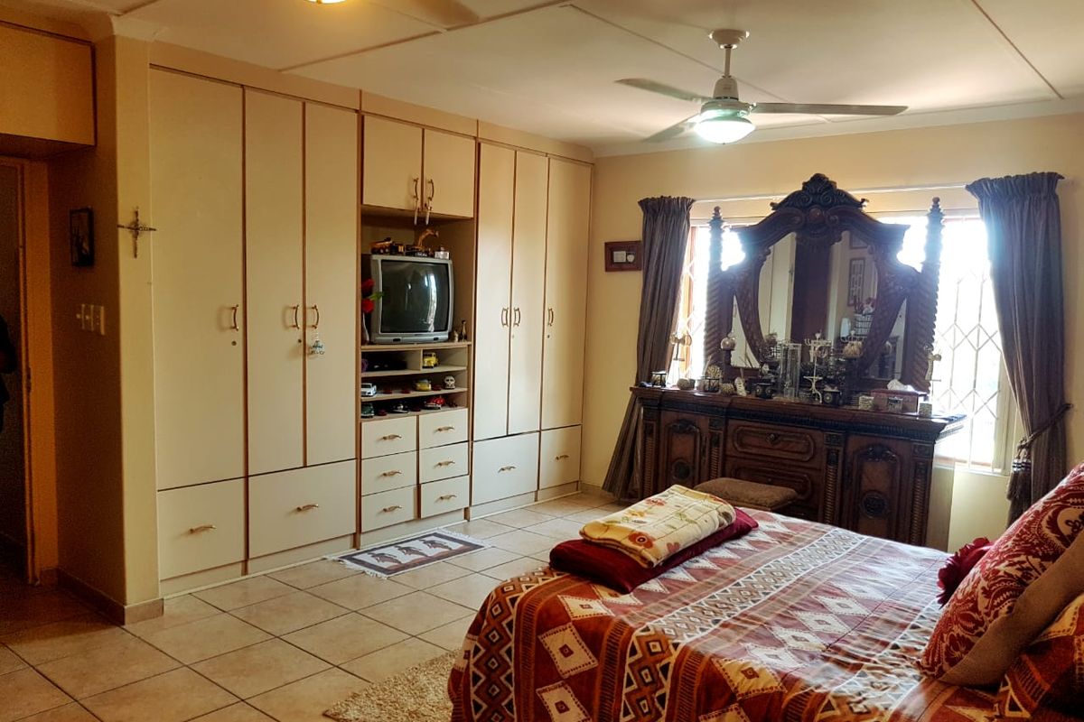 Spacious bedroom featuring extensive built-in cabinetry, tiled flooring, and a ceiling fan, offering ample storage and functional living space.