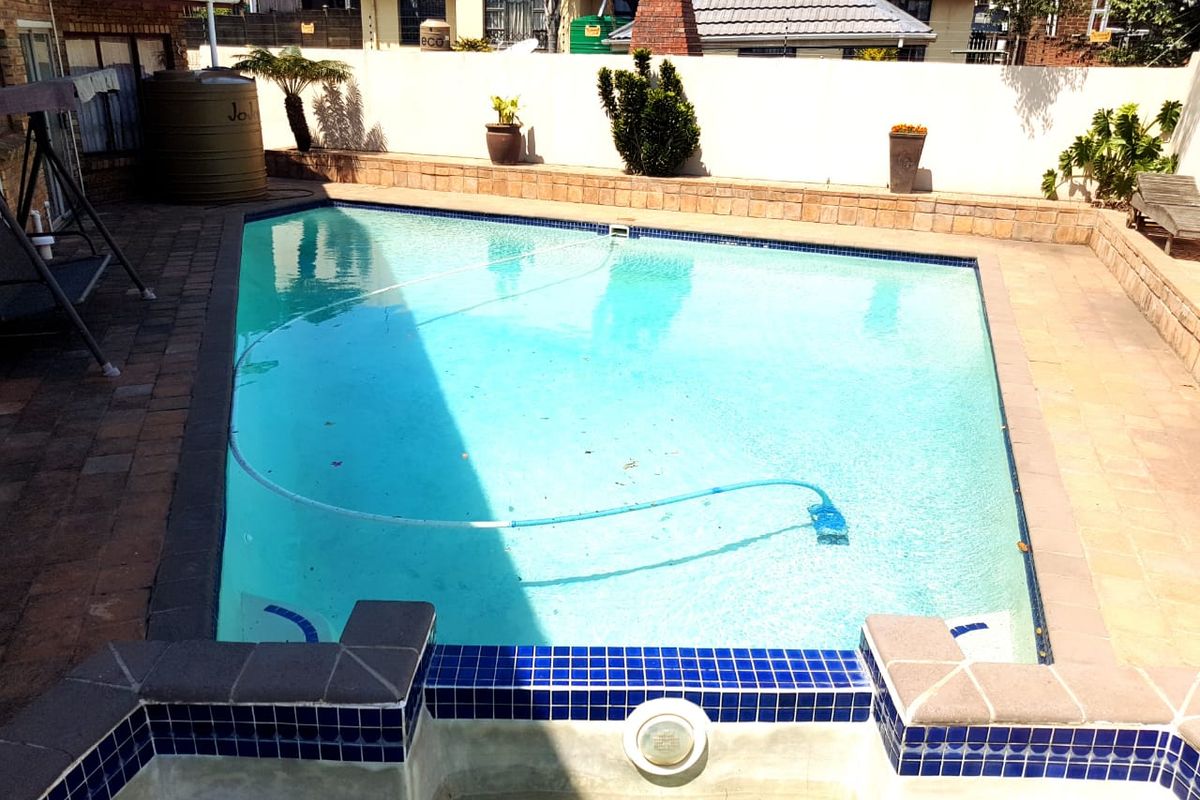 A well-maintained swimming pool area featuring paved surrounds, a retaining wall, and integrated pool lighting, providing a functional outdoor entertainment space.