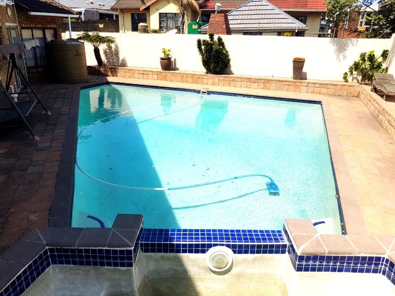 A well-maintained swimming pool area featuring paved surrounds, a retaining wall, and integrated pool lighting, providing a functional outdoor entertainment space.