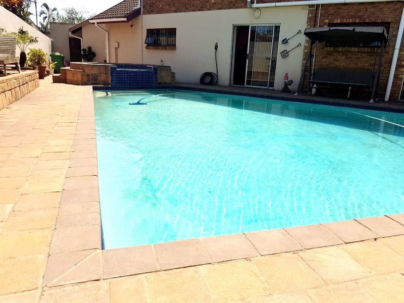 Outdoor pool area featuring a tiled surround, raised water feature, and direct access to the home via sliding glass doors.