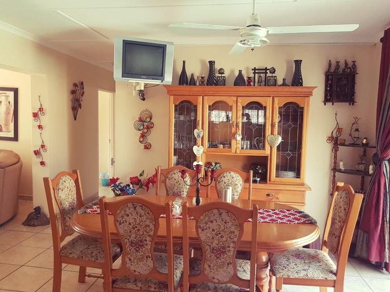 A traditional dining room featuring tiled flooring and a ceiling fan, providing a functional space for family meals.