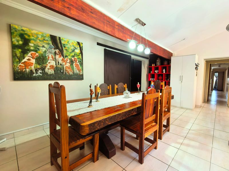Dining room featuring tiled flooring, an exposed timber ceiling beam, built-in shelving, and a built-in cupboard, with visible ceiling water staining.