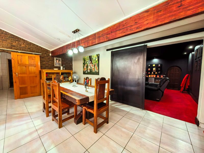 Dining area featuring exposed brickwork, a prominent timber ceiling beam, tiled flooring, and a sliding barn door leading to an adjacent room.