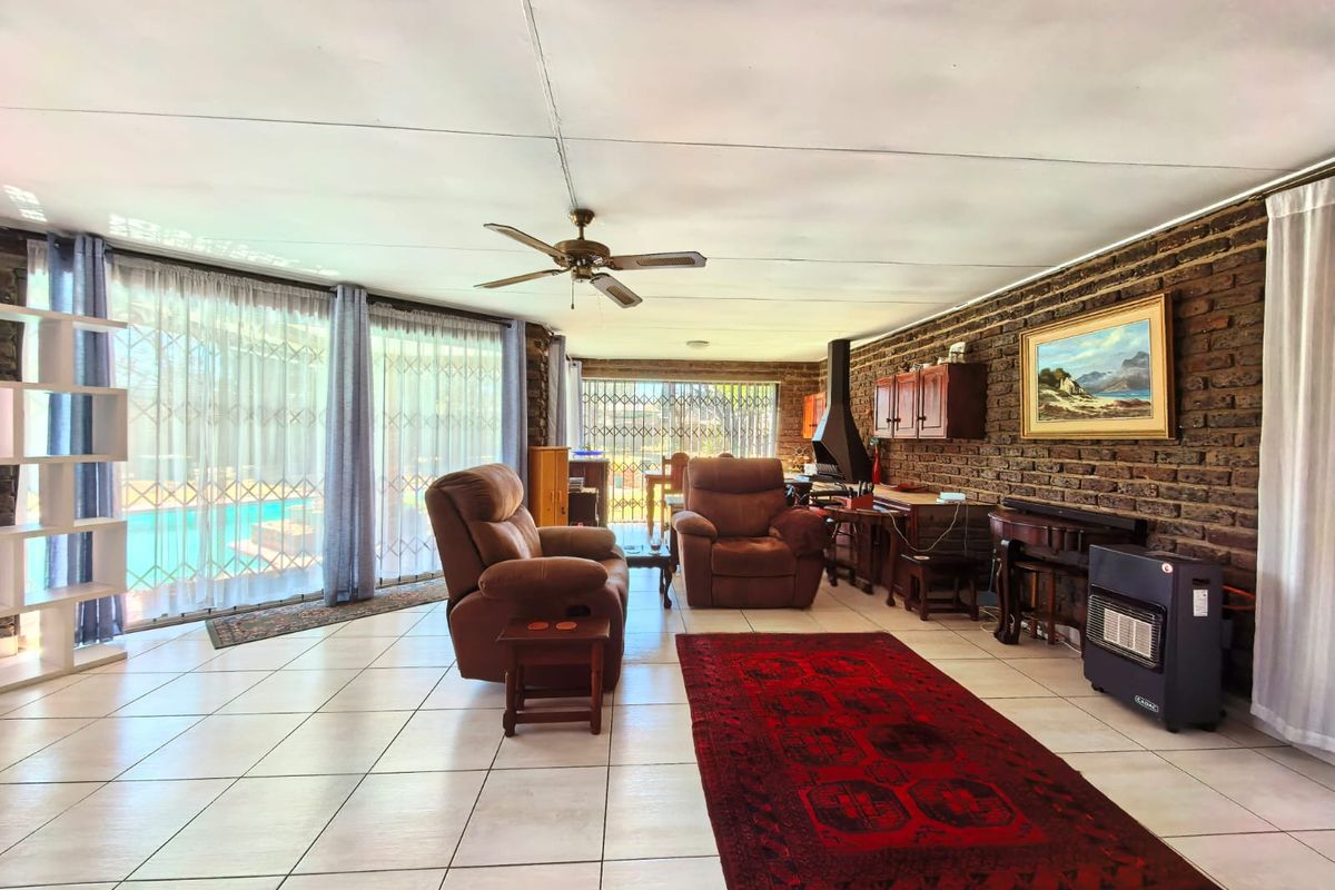 Spacious living room featuring an exposed brick wall, built-in fireplace, tiled flooring, and large sliding glass doors providing access to the pool area.
